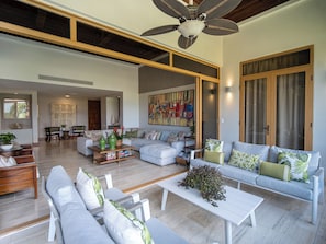 A spacious living area with a large sofa set, a coffee table, and a ceiling fan.