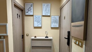 A hallway with a marble floor, wooden doors, and wall-mounted maps of New York, Oslo, and Amsterdam. - Luxury apartment in Agdal free Netflix and garage (Rabat)