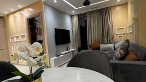 A modern living room with a marble table, a grey sofa, and a TV mounted on the wall. - Luxury apartment in Agdal free Netflix and garage (Rabat)