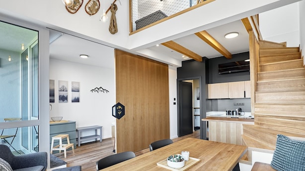 A modern interior with a wooden dining table, seating, and a staircase leading to an upper level. - Apartment Kozlík by Interhome (Abertamy)