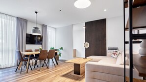 Een moderne woonkamer met een bank, eettafel, stoelen en een televisie.