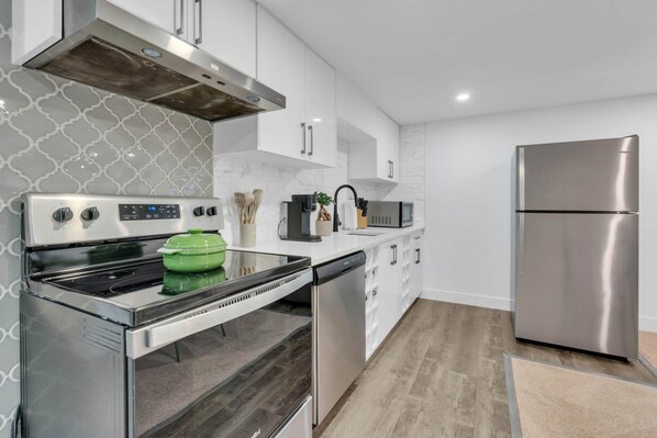 Una cocina moderna con electrodomésticos de acero inoxidable, armarios blancos y un salpicadero decorativo.