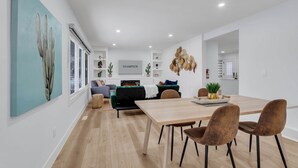Un salon moderne avec un canapé, une table à manger et des chaises, et un téléviseur fixé au mur.