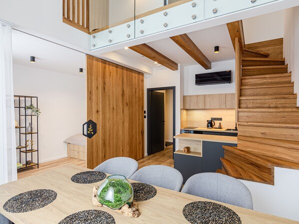 A modern kitchen with wooden accents, a built-in stove, and a black TV mounted above the counter.
