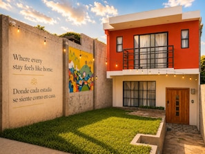 Un edificio moderno con fachada roja, un mural atractivo y un césped bien cuidado.