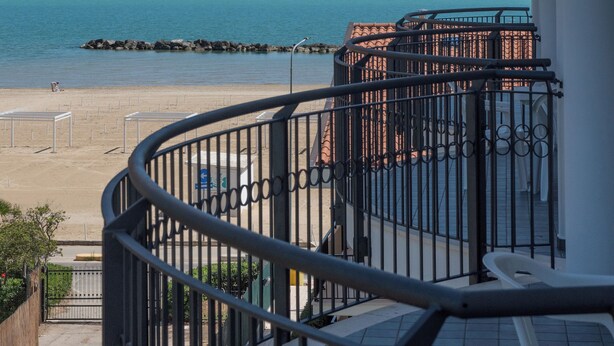 A balcony with a view of the sea and a sailboat.