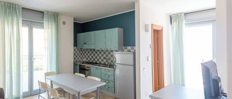 Una cocina compacta con zona de comedor, un refrigerador pequeño y una mesa con sillas.