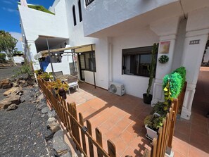 A white building with a tiled patio, a wooden fence, and potted plants. - Casa Samba, 2 Bedrooms and Pool (La Oliva)