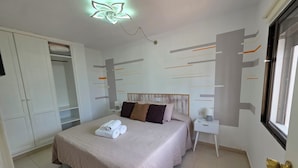 Ein Schlafzimmer mit einem Bett, einem Nachttisch, einem Kleiderschrank und einem Deckenventilator.