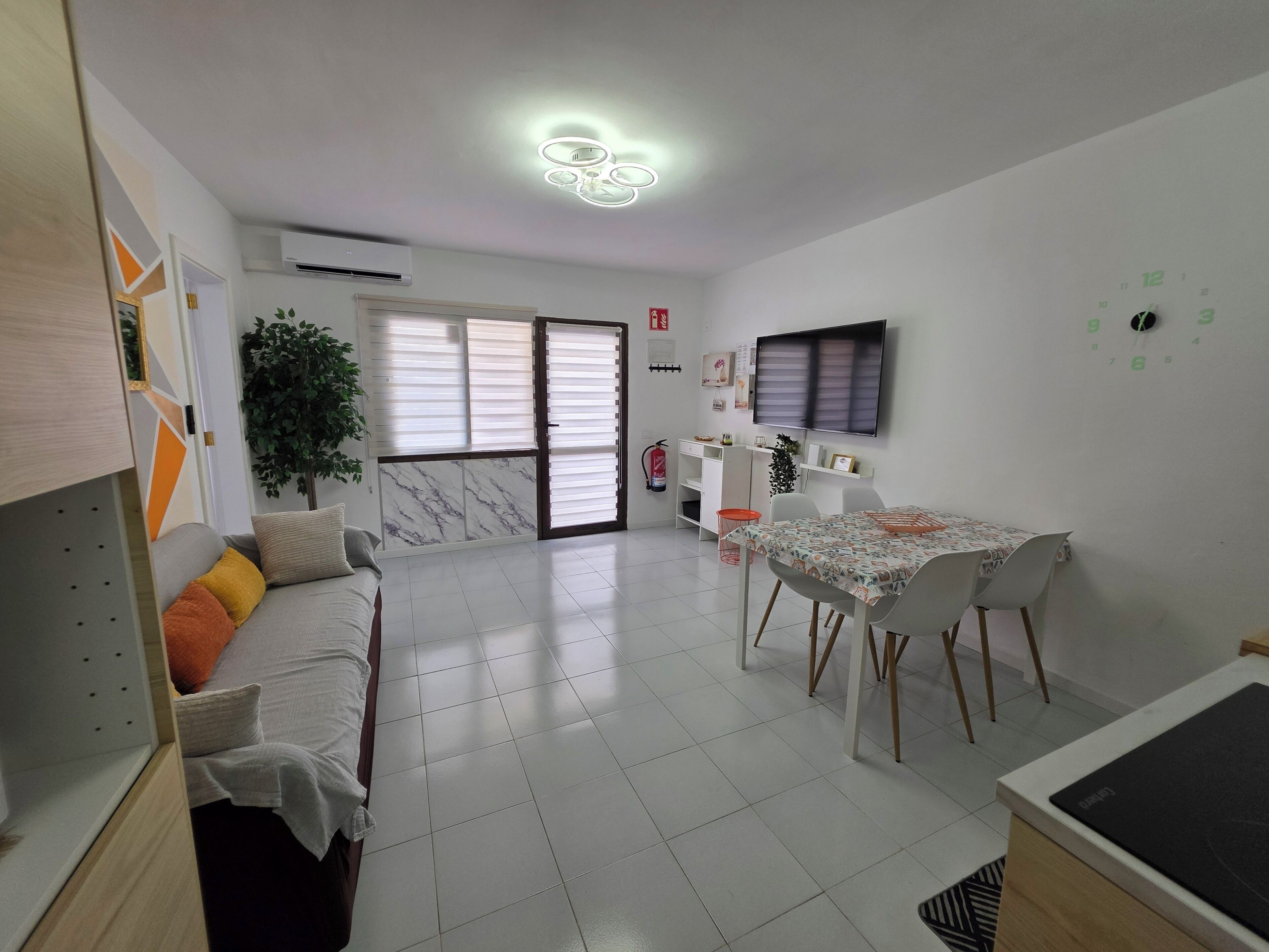 A modern living room with a sofa, dining table, and TV.