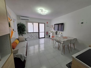 A modern living room with a sofa, dining table, and TV. - Casa Samba, 2 Bedrooms and Pool (La Oliva)