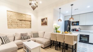 Una sala moderna con un sofá, una mesa de centro y una pequeña cocina con una mesa de comedor y sillas.