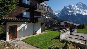 Un chalet à deux étages doté d’un balcon, d’un garage et offrant une vue sur la montagne.