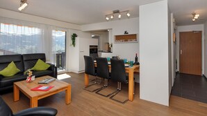 Un salon moderne comprenant un canapé, une table basse et un coin repas avec des chaises.