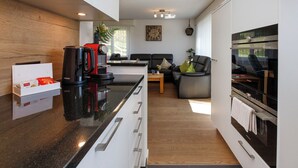 Une cuisine moderne avec un plan de travail noir, des meubles blancs et un four encastré.