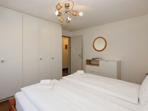 A bedroom with a bed, a wardrobe, a mirror, and a ceiling light fixture.