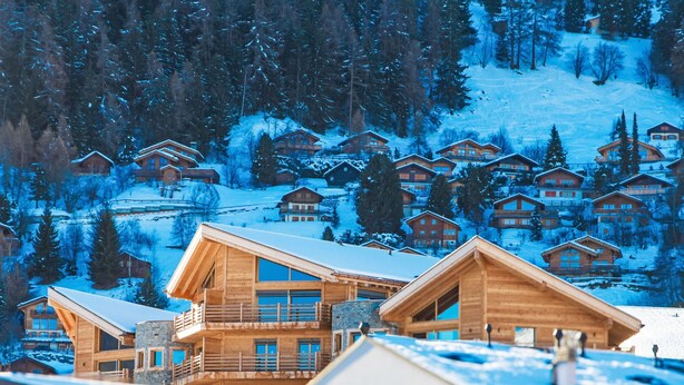 A cluster of wooden cabins with balconies, set against a snowy mountain backdrop. - Bike & Ski 301 by Interhome (Nendaz)