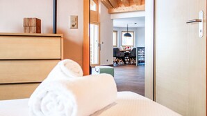 A hotel room with a bed, a wooden dresser, and a view of the dining area. - Bike & Ski 301 by Interhome (Nendaz)