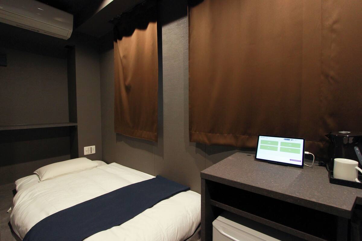 A hotel room with a bed, a desk with a computer, and a coffee maker.