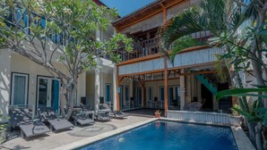 Zona de piscina con sillas de descanso y un edificio con balcones.