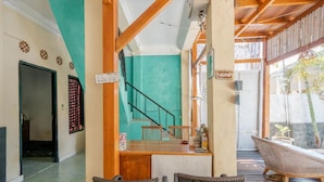 Un hall con escalera, mostrador de recepción y mobiliario de mimbre.
