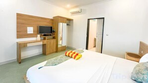 Una habitación de hotel con cama, escritorio, televisor y armario.