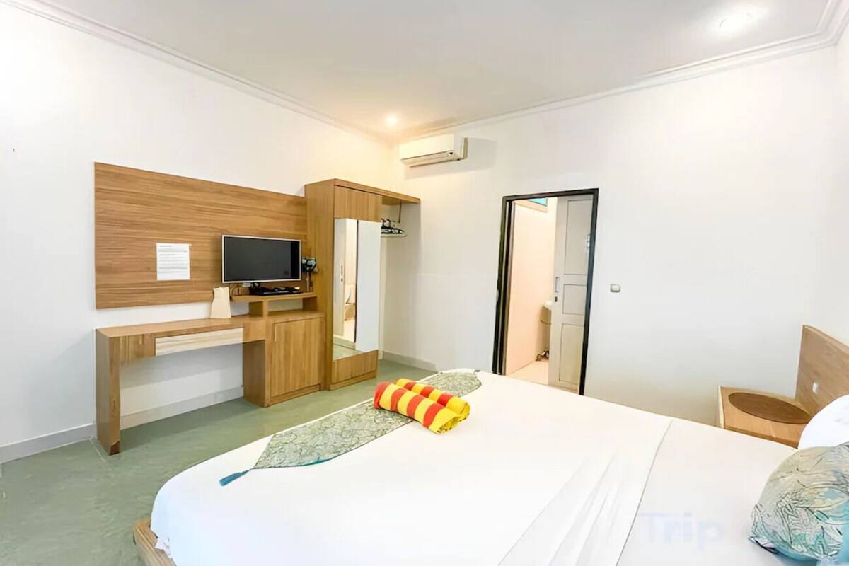 A hotel room with a bed, a desk, a TV, and a wardrobe.