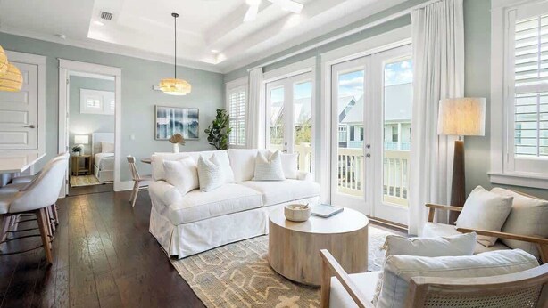 A spacious living room with a white sofa, a round coffee table, and a ceiling fan.