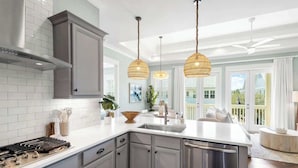 A modern kitchen with grey cabinets, a stainless steel range, and a central island with a sink.