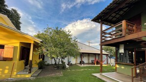 A courtyard with a yellow building, a white building, and a wooden structure with a balcony.