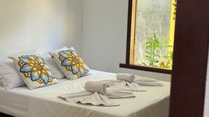 A neatly made bed with white linens and two decorative pillows with floral patterns.