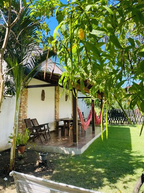 A patio area with a wooden table and chairs, a hammock, and a potted plant. - Canto Itaúnas  (Conceicao da Barra)