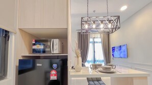 Cocina moderna con refrigerador, microondas y comedor con taburete y mesa.