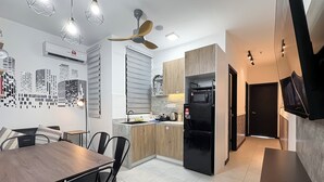 Una cocina moderna con comedor, que incluye una mesa y sillas de madera, un refrigerador negro y un ventilador de techo.