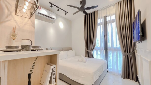 Una habitación de hotel moderna con cama, tocador con espejo, ventilador de techo y un ventanal con cortinas.