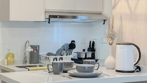 Una cocina moderna con armarios blancos, una campana extractora de acero inoxidable y una encimera blanca.