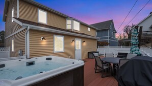 A hot tub on a wooden deck with a house in the background.