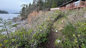 En stuga med en träveranda som vetter mot en skogbeklädd strand.