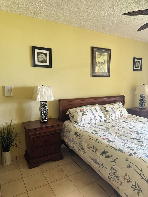 A bedroom with a bed, nightstands, a lamp, and framed pictures on the wall.
