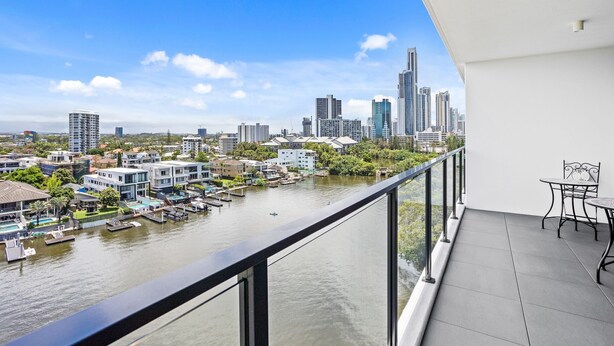 Varanda com vista para a cidade, onde se pode ver um rio, edifícios modernos e uma área de refeições.