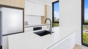 Cozinha moderna com armários brancos, pia preta e janela com vista para a cidade.