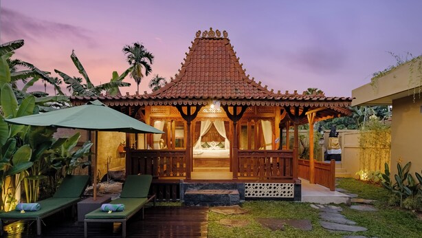 A traditional building with a tiled roof, a wooden porch, and a pool area with lounge chairs.