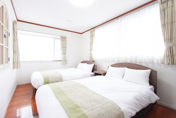A hotel room with two beds, wooden flooring, a large window with curtains, and a wooden headboard. - HOTEL DO-YA BEPPU Bekkan (Beppu)