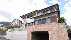 A modern two-story house with a stone facade, a garage, and a balcony.