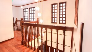 A wooden staircase with a railing, a wooden floor, and a wall with windows and a decorative panel.