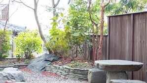 A garden with stone benches, a wooden fence, and a variety of plants.