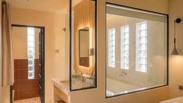 A modern bathroom with a large mirror, a sink, and a bathtub.