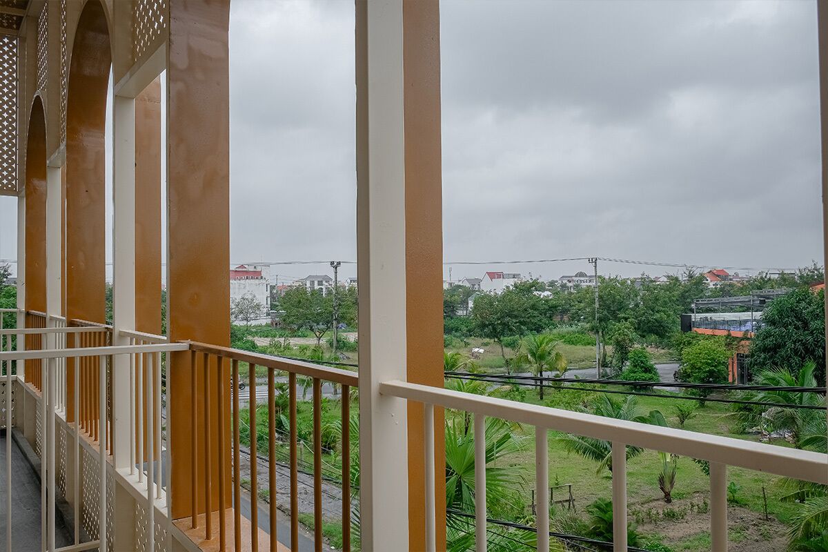 A balcony with a view of a residential area, including houses and greenery.