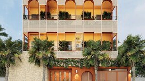 Un hotel a più piani con balconi, palme e facciata in pietra.