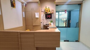 A reception area with a wooden counter, a digital clock, and a blue elevator door. - Hotel Stay Inn near Bhiwandi Thane Railway Station (Bhiwandi)